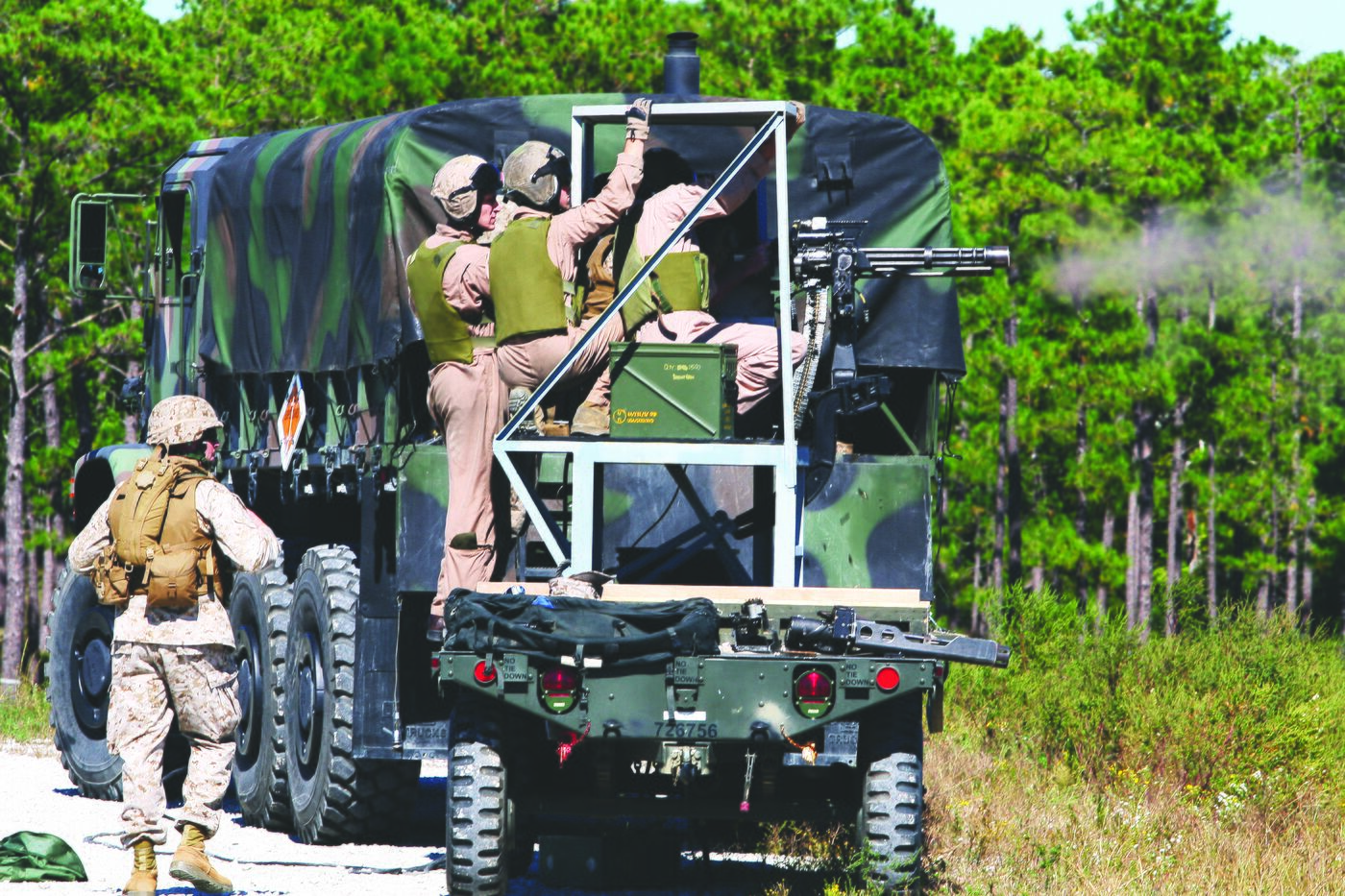 Marines firing a mounted machine gun from the bed of a truck