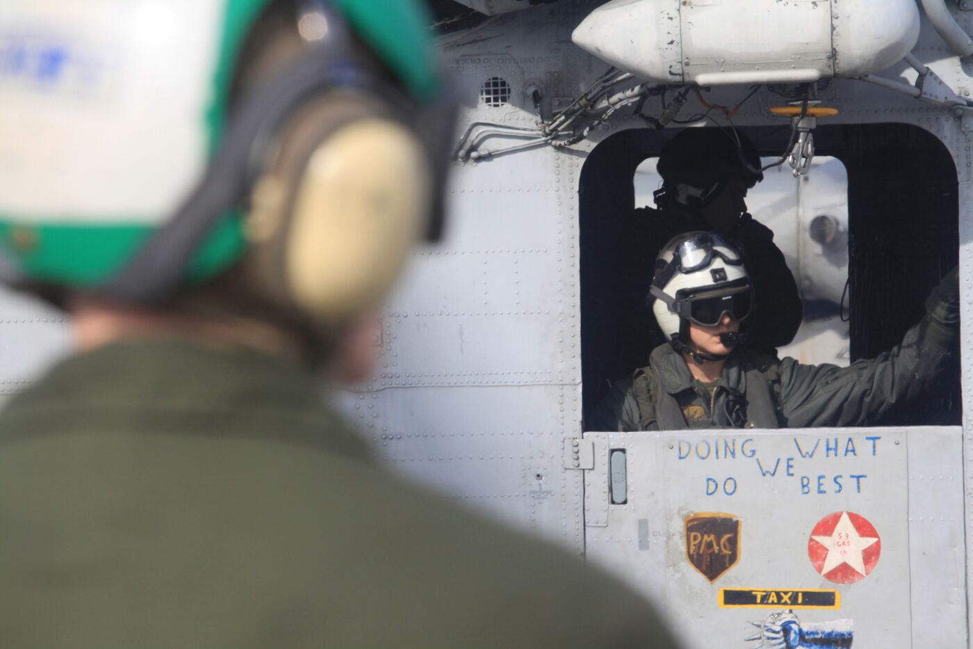 A helmeted aircrew member looking out a helicopter door